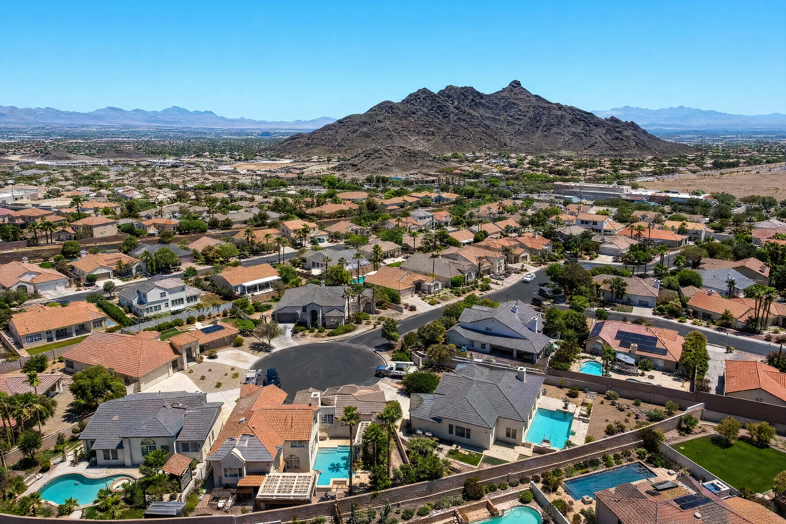 Aerial view of a Henderson, Nevada neighbourhood of concrete tile roofs at golden hour with Black Mountain behind