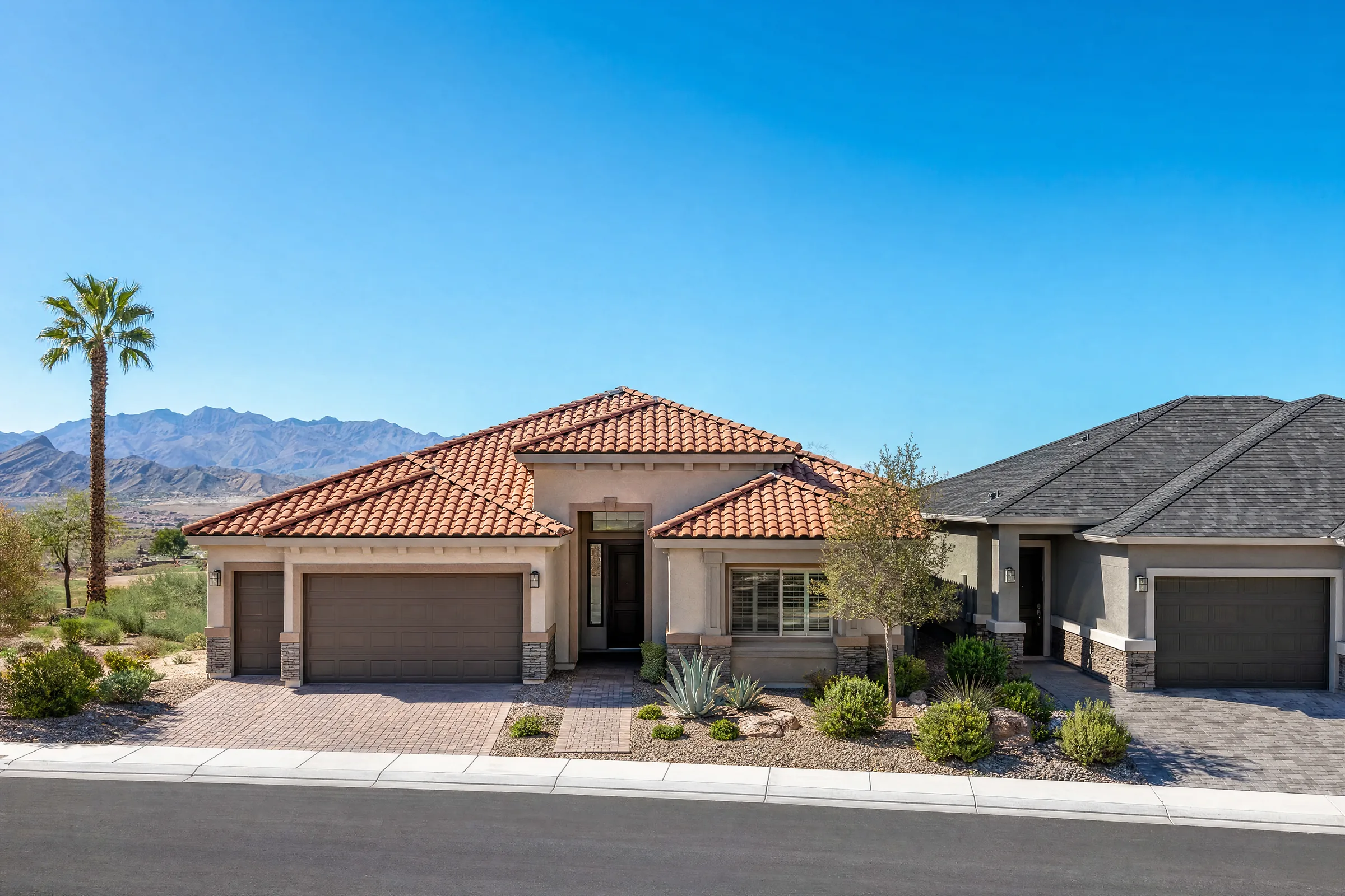Two Las Vegas homes side by side, one with a terracotta tile roof and one with a charcoal shingle roof, under a clear blue sky