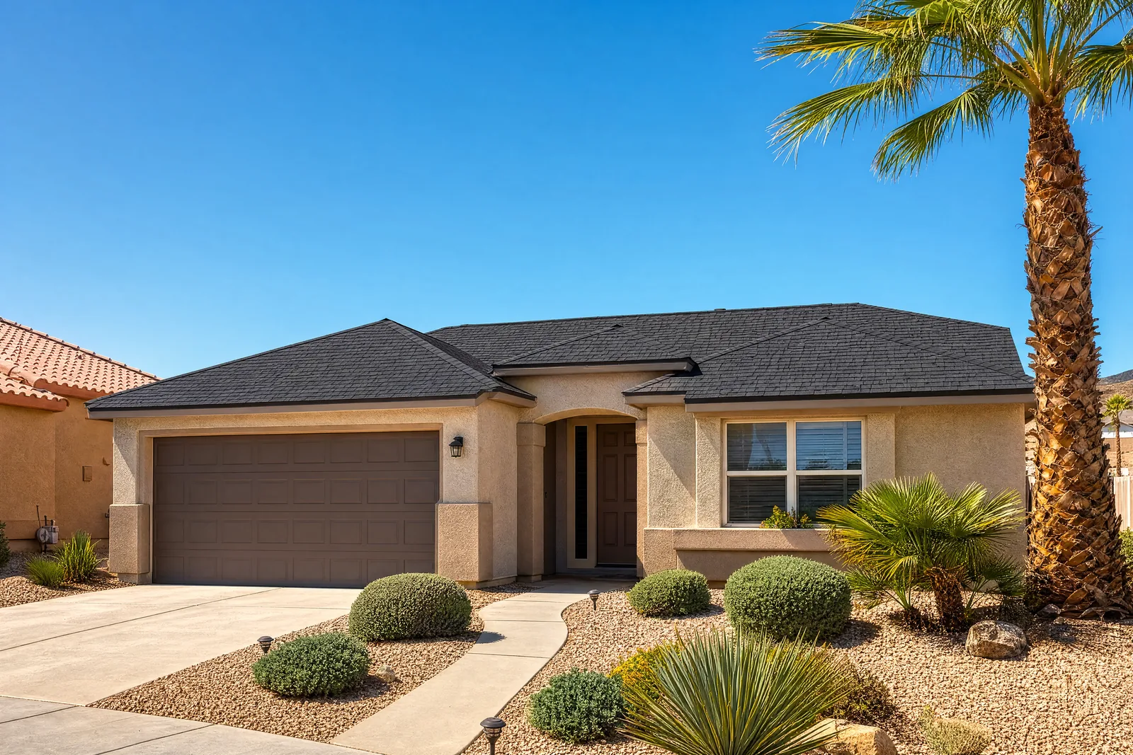 Las Vegas stucco home with a new charcoal architectural asphalt shingle roof under a clear blue sky